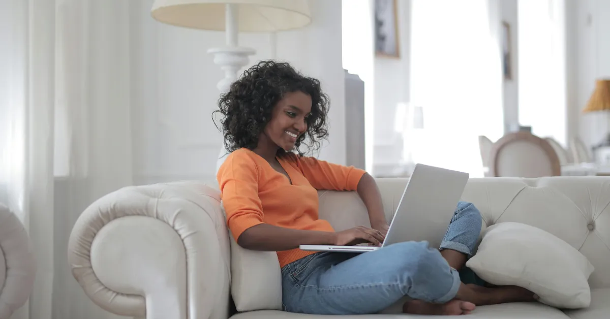 Woman Sitting on White Couch Using Laptop